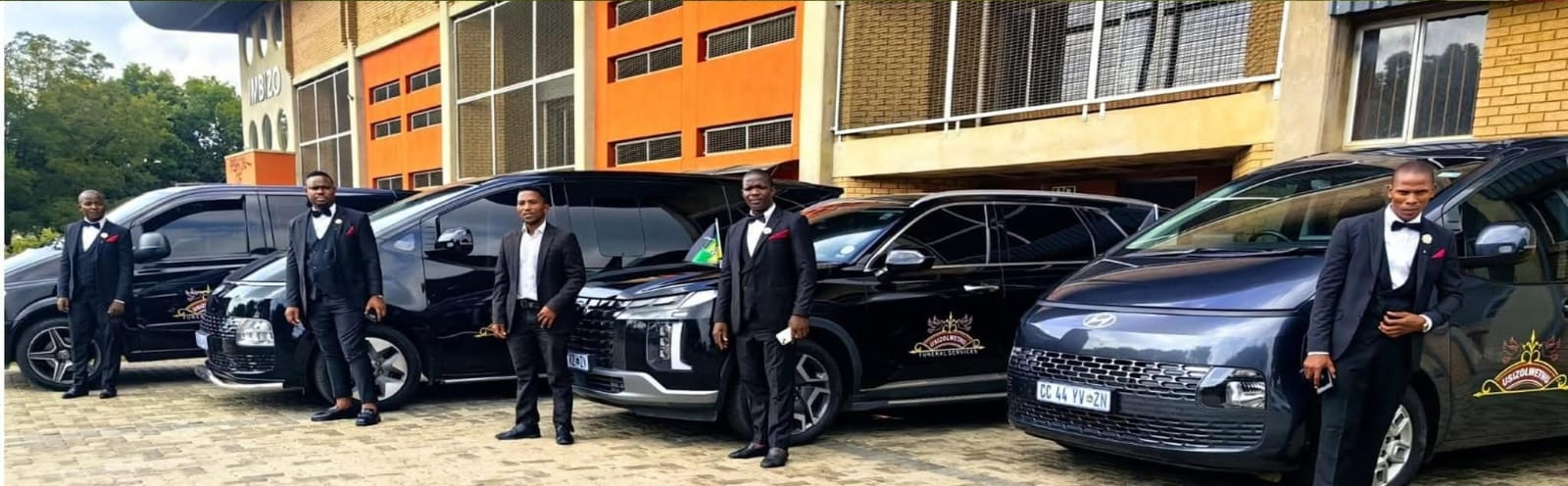 Usizolwethu Funeral Services team in formal suits with their fleet of vehicles