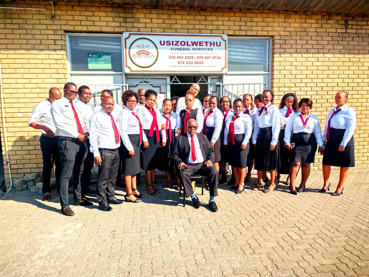 Usizolwethu Funeral Services staff standing in front of their branch in uniform